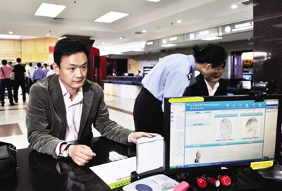 昨日，一名市民在北京出入境管理总队的办证大厅申请办理电子护照时，工作人员采集他的指纹。当日起，全国公安机关统一启用签发电子普通护照。新华社记者 李文 摄